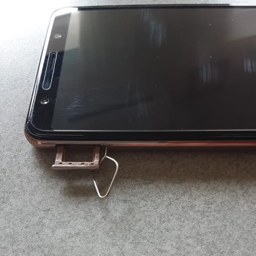 スマートフォンにSIMピンを差し込んでSIMスロットを開ける